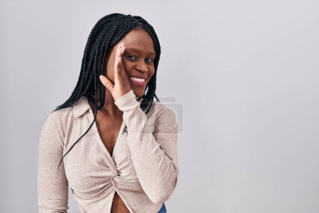 Foto de African woman with braids standing over white background hand on mouth telling secret rumor, whispering malicious talk conversation - Imagen libre de derechos