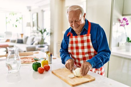 Photo for Senior man smiling confident cutting onion at kitchen - Royalty Free Image