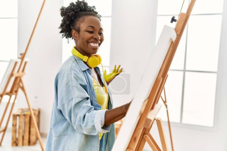 Téléchargez les photos : Jeune artiste afro-américaine femme souriante peinture heureuse avec les mains au studio d'art. - en image libre de droit