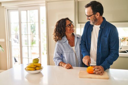 Téléchargez les photos : Moyen âge couple hispanique souriant confiant coupe orange à la cuisine - en image libre de droit