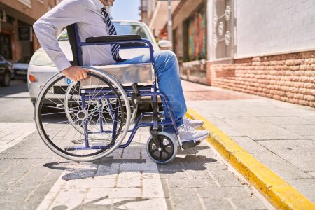Foto de Hombre hispano de mediana edad con ropa de negocios sentado en silla de ruedas en la calle - Imagen libre de derechos