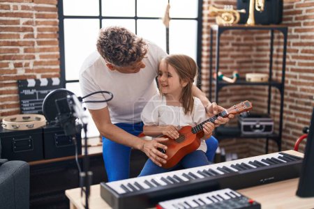 Foto de Padre e hija tocando ukelele en el estudio de música - Imagen libre de derechos