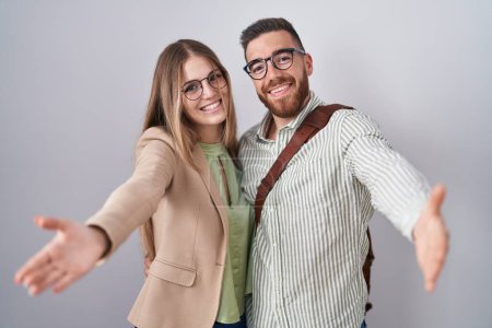 Téléchargez les photos : Young couple standing over white background looking at the camera smiling with open arms for hug. cheerful expression embracing happiness. - en image libre de droit