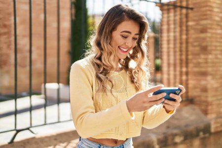 Téléchargez les photos : Young woman smiling confident watching video on smartphone at street - en image libre de droit