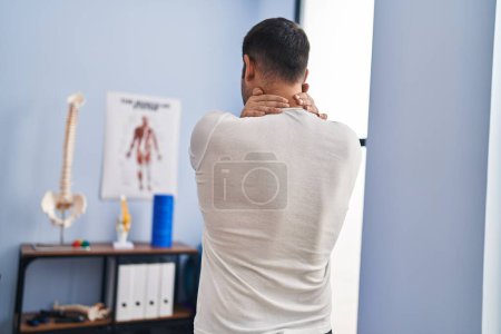 Photo for Young hispanic man injured physiotherapy patient suffering for neck ache at rehab clinic - Royalty Free Image