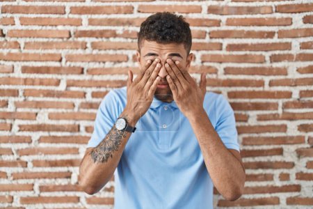 Téléchargez les photos : Brazilian young man standing over brick wall rubbing eyes for fatigue and headache, sleepy and tired expression. vision problem - en image libre de droit