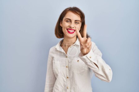 Photo for Young beautiful woman standing casual over blue background showing and pointing up with fingers number two while smiling confident and happy. - Royalty Free Image