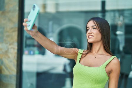 Téléchargez les photos : Jeune belle femme hispanique souriant confiant faire selfie par le smartphone à la rue - en image libre de droit