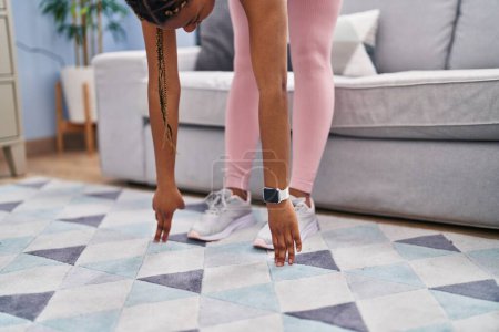 Téléchargez les photos : African american woman stretching legs at home - en image libre de droit