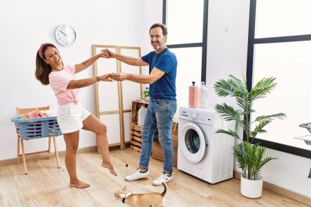 Foto de Hombre y mujer de mediana edad pareja bailando y lavando ropa en la lavandería - Imagen libre de derechos