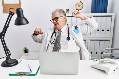 Photo for Senior caucasian man wearing doctor uniform and stethoscope at the clinic stretching back, tired and relaxed, sleepy and yawning for early morning - Royalty Free Image
