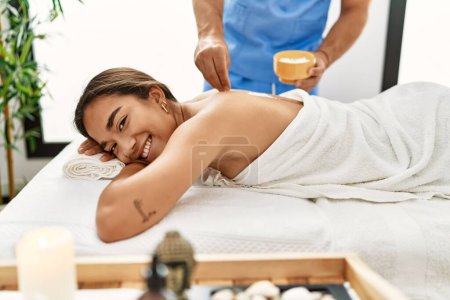 Téléchargez les photos : Latin homme et femme portant physiothérapie massage retour en utilisant du sel au centre de beauté - en image libre de droit