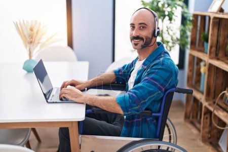 Téléchargez les photos : Jeune homme hispanique assis sur fauteuil roulant télétravail à la maison - en image libre de droit