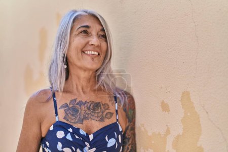 Foto de Mujer de pelo gris de mediana edad sonriendo confiada mirando hacia un lado sobre un fondo blanco aislado - Imagen libre de derechos