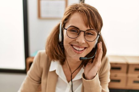 Téléchargez les photos : Jeune caucasien centre d'appels agent femme souriant heureux de travailler au bureau. - en image libre de droit
