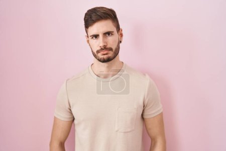 Foto de Hombre hispano con barba de pie sobre fondo rosa deprimido y preocupado por la angustia, llorando enojado y asustado. expresión triste. - Imagen libre de derechos