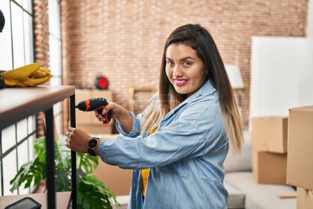 Téléchargez les photos : Young beautiful plus size woman smiling confident repairing shelving at new home - en image libre de droit