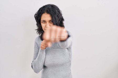 Photo for Hispanic woman with dark hair standing over isolated background punching fist to fight, aggressive and angry attack, threat and violence - Royalty Free Image