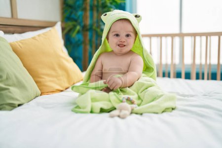 Photo for Adorable caucasian baby wearing funny towel sitting on bed at bedroom - Royalty Free Image