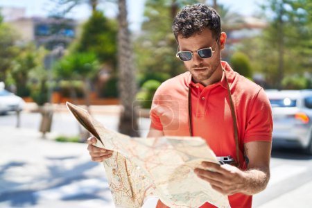 Foto de Joven hispano hombre turístico holding mapa de la ciudad en la calle - Imagen libre de derechos