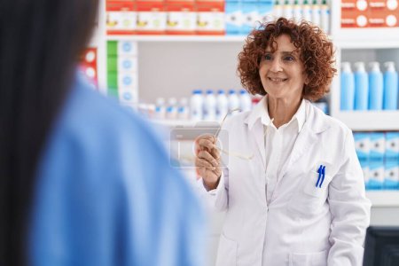Foto de Dos mujeres farmacéuticas y cliente hablando en la farmacia - Imagen libre de derechos