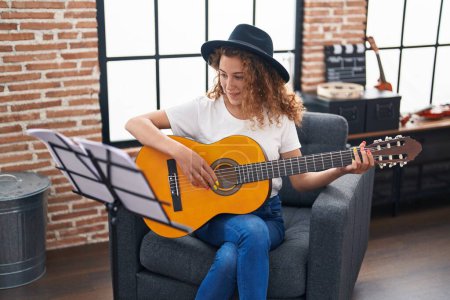 Photo for Young beautiful hispanic woman musician playing classical guitar at music studio - Royalty Free Image