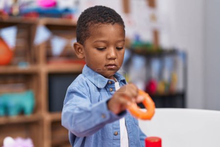 Photo for African american boy holding plastic hoop toy standing at kindergarten - Royalty Free Image