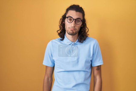 Photo for Young hispanic man standing over yellow background depressed and worry for distress, crying angry and afraid. sad expression. - Royalty Free Image