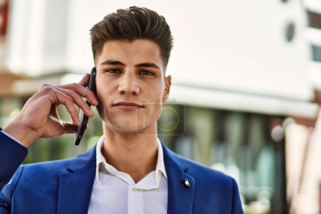 Téléchargez les photos : Jeune homme parlant sur le smartphone portant un costume à la rue - en image libre de droit