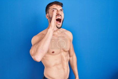 Photo for Handsome hispanic man standing shirtless shouting and screaming loud to side with hand on mouth. communication concept. - Royalty Free Image