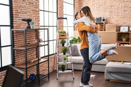 Photo for Young man and woman couple hugging each other standing at new home - Royalty Free Image