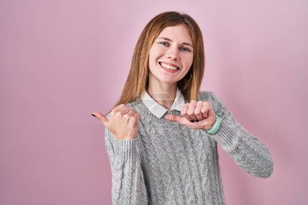 Photo for Beautiful woman standing over pink background pointing to the back behind with hand and thumbs up, smiling confident - Royalty Free Image