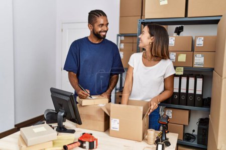 Téléchargez les photos : Homme et femme partenaires commerciaux emballage paquet de travail à l'entrepôt - en image libre de droit