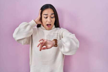 Photo for Young south asian woman standing over pink background looking at the watch time worried, afraid of getting late - Royalty Free Image