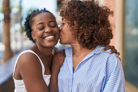 Téléchargez les photos : African american women mother and daughter hugging each other kissing at street - en image libre de droit