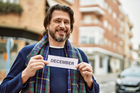 Foto de Hombre guapo de mediana edad sosteniendo la pancarta de diciembre en la ciudad - Imagen libre de derechos