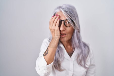 Photo for Middle age woman with tattoos wearing glasses standing over white background covering one eye with hand, confident smile on face and surprise emotion. - Royalty Free Image