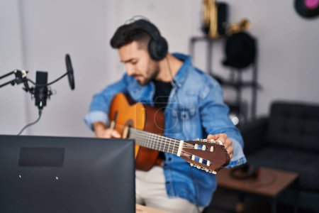 Téléchargez les photos : Jeune homme hispanique chantant une chanson jouant de la guitare classique au studio de musique - en image libre de droit
