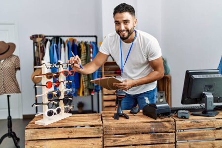 Photo for Young arab man shopkeeper touching glasses working at clothing store - Royalty Free Image