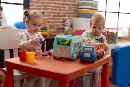 Foto de Adorable chica y niño jugando con juguetes en la mesa en el jardín de infantes - Imagen libre de derechos