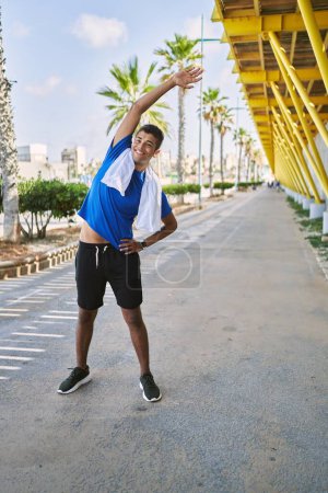 Téléchargez les photos : Young hispanic man stretching body muscles outdoors - en image libre de droit