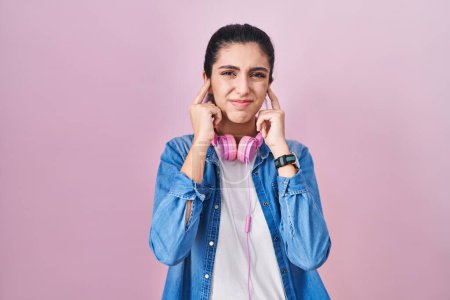 Photo for Young beautiful woman standing over pink background covering ears with fingers with annoyed expression for the noise of loud music. deaf concept. - Royalty Free Image
