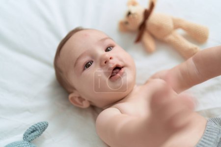 Foto de Adorable niño acostado en la cama con oso de peluche en el dormitorio - Imagen libre de derechos