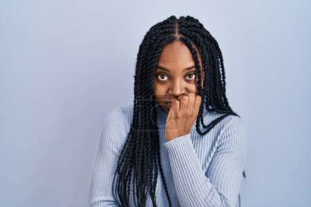 Photo for African american woman standing over blue background looking stressed and nervous with hands on mouth biting nails. anxiety problem. - Royalty Free Image
