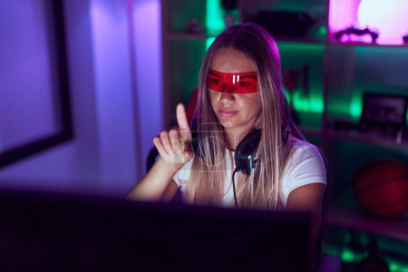 Téléchargez les photos : Jeune belle hispanique femme streamer jouer jeu vidéo en utilisant des lunettes de réalité virtuelle à la salle de jeu - en image libre de droit