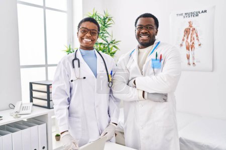 Téléchargez les photos : Jeunes médecins afro-américains travaillant à la clinique médicale regardant positif et heureux debout et souriant avec un sourire confiant montrant les dents - en image libre de droit