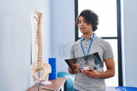 Photo for Young hispanic man physiotherapist looking xray at rehab clinic - Royalty Free Image