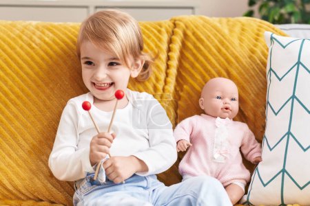 Photo for Adorable caucasian girl smiling confident sitting on sofa with baby doll at home - Royalty Free Image