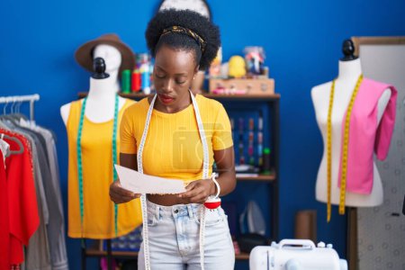 Téléchargez les photos : African american woman tailor reading document at sewing studio - en image libre de droit