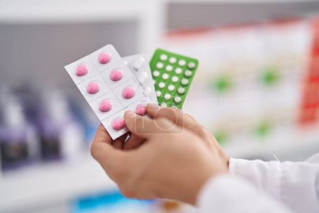 Téléchargez les photos : Jeune femme pharmacienne tenant des pilules à la pharmacie - en image libre de droit
